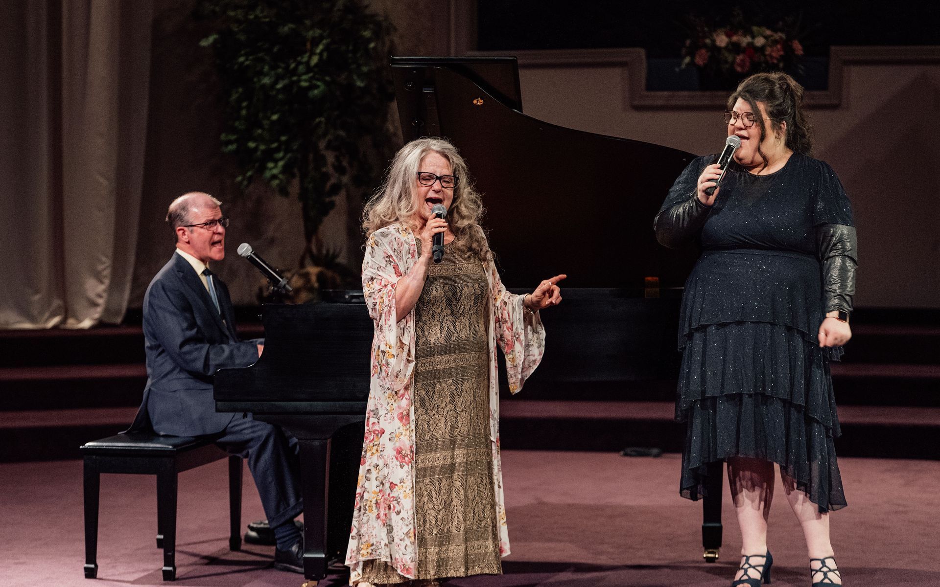 A man and two women are standing on a porch holding hands