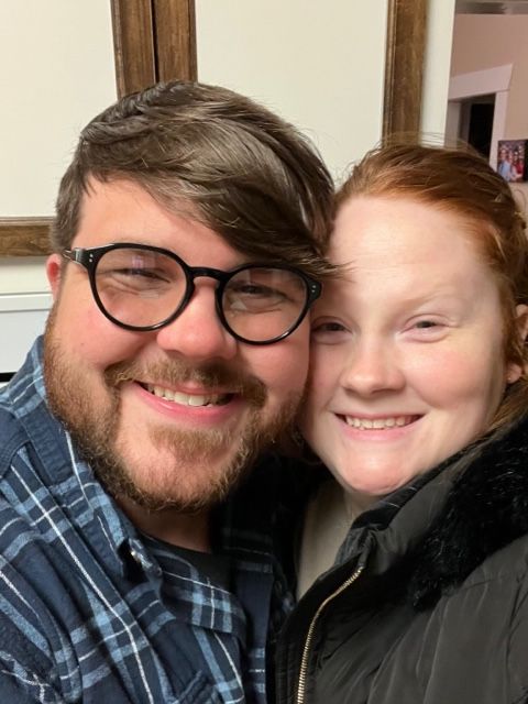 A man and a woman are posing for a picture and smiling for the camera.