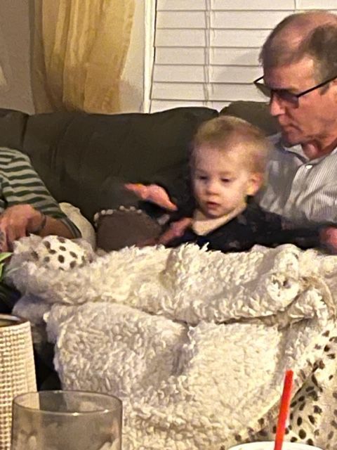 A man is holding a baby while sitting on a couch.