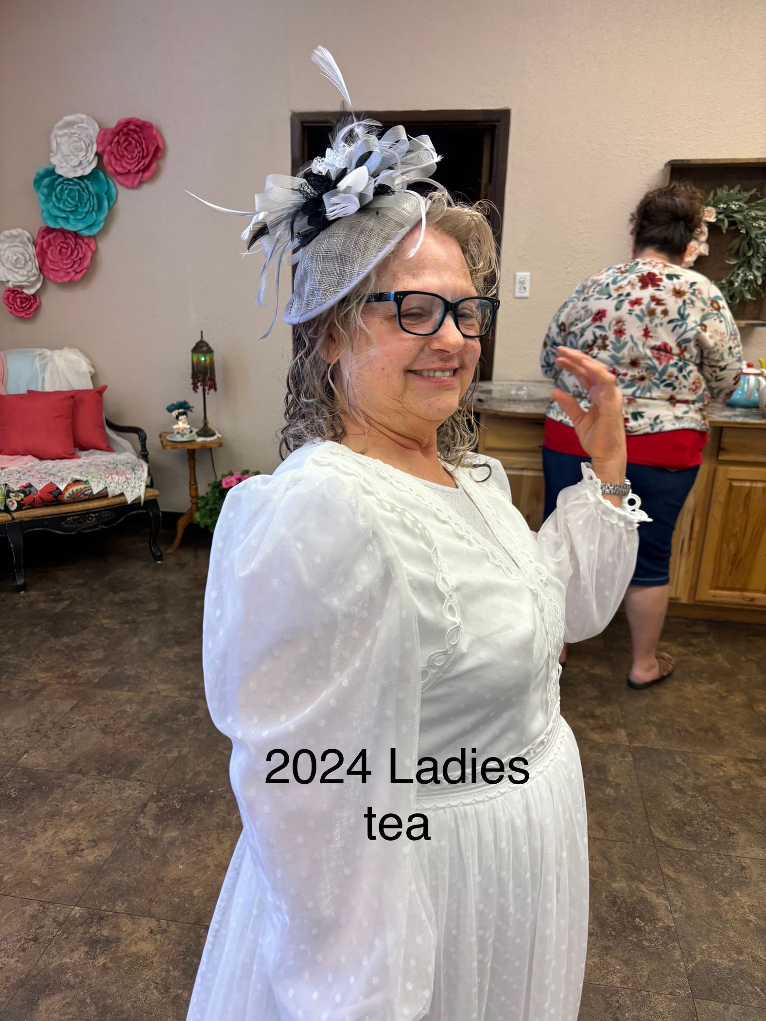 A woman in a white dress and hat is standing in a room.