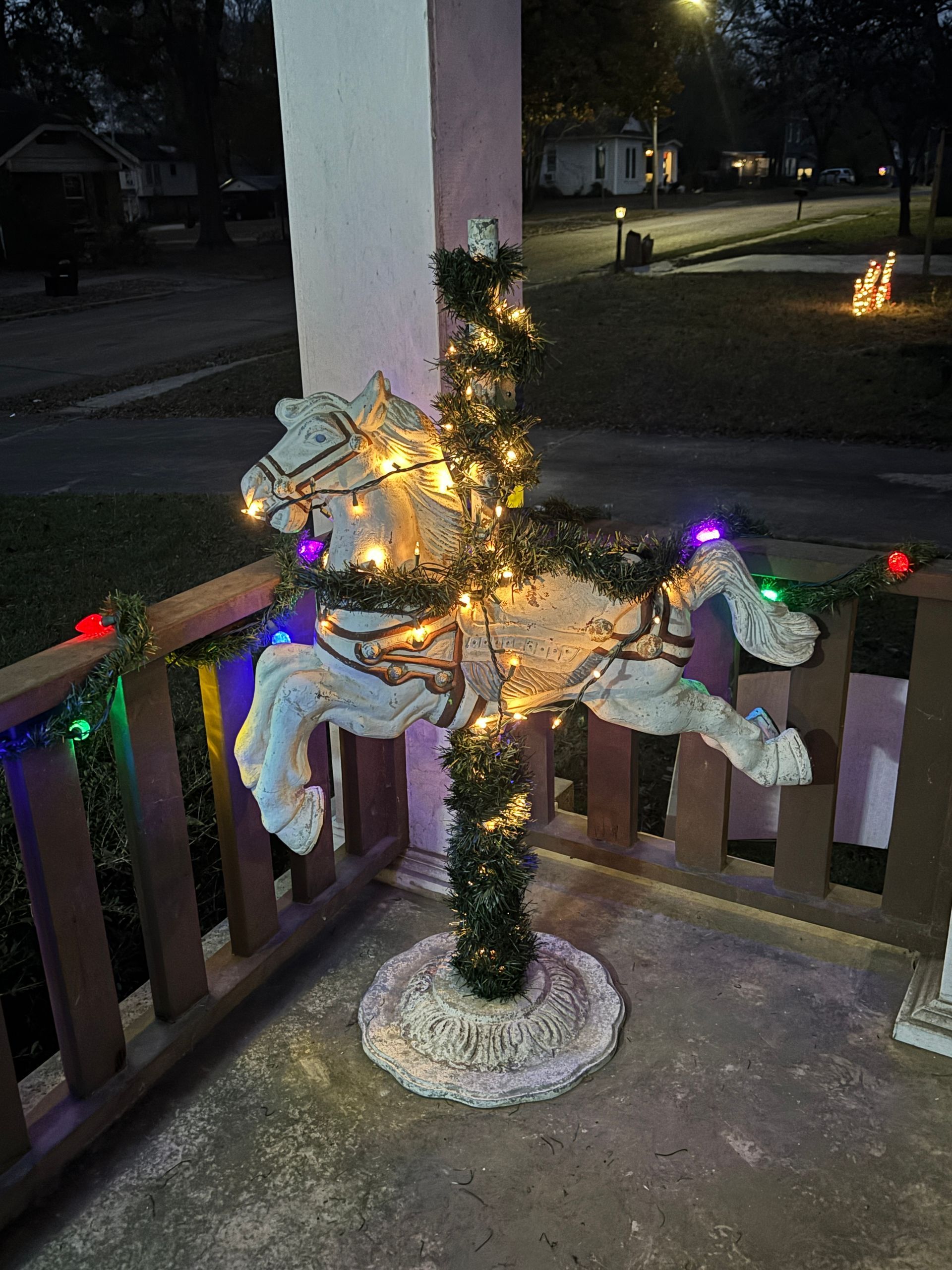 Carousel horse Christmas decoration with lights, on a porch, at night.