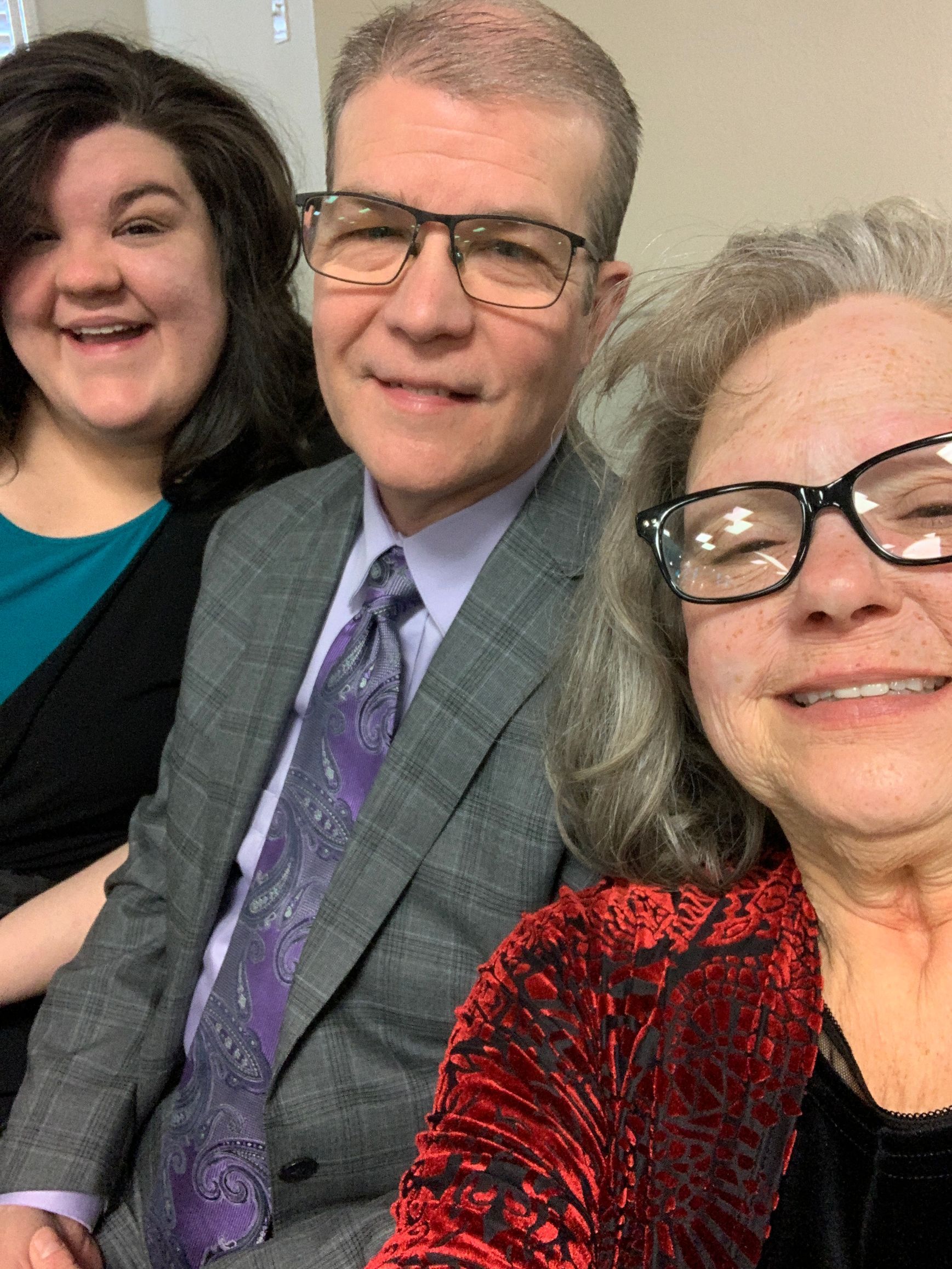 A man in a suit and tie is taking a selfie with two women.