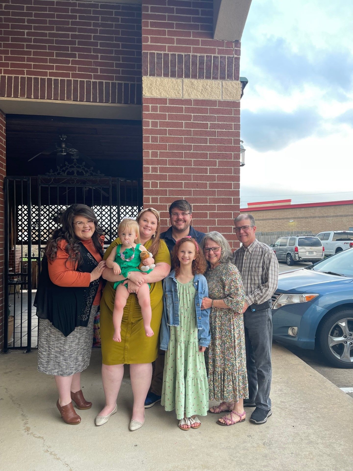 A group of people are posing for a picture in front of a brick building.