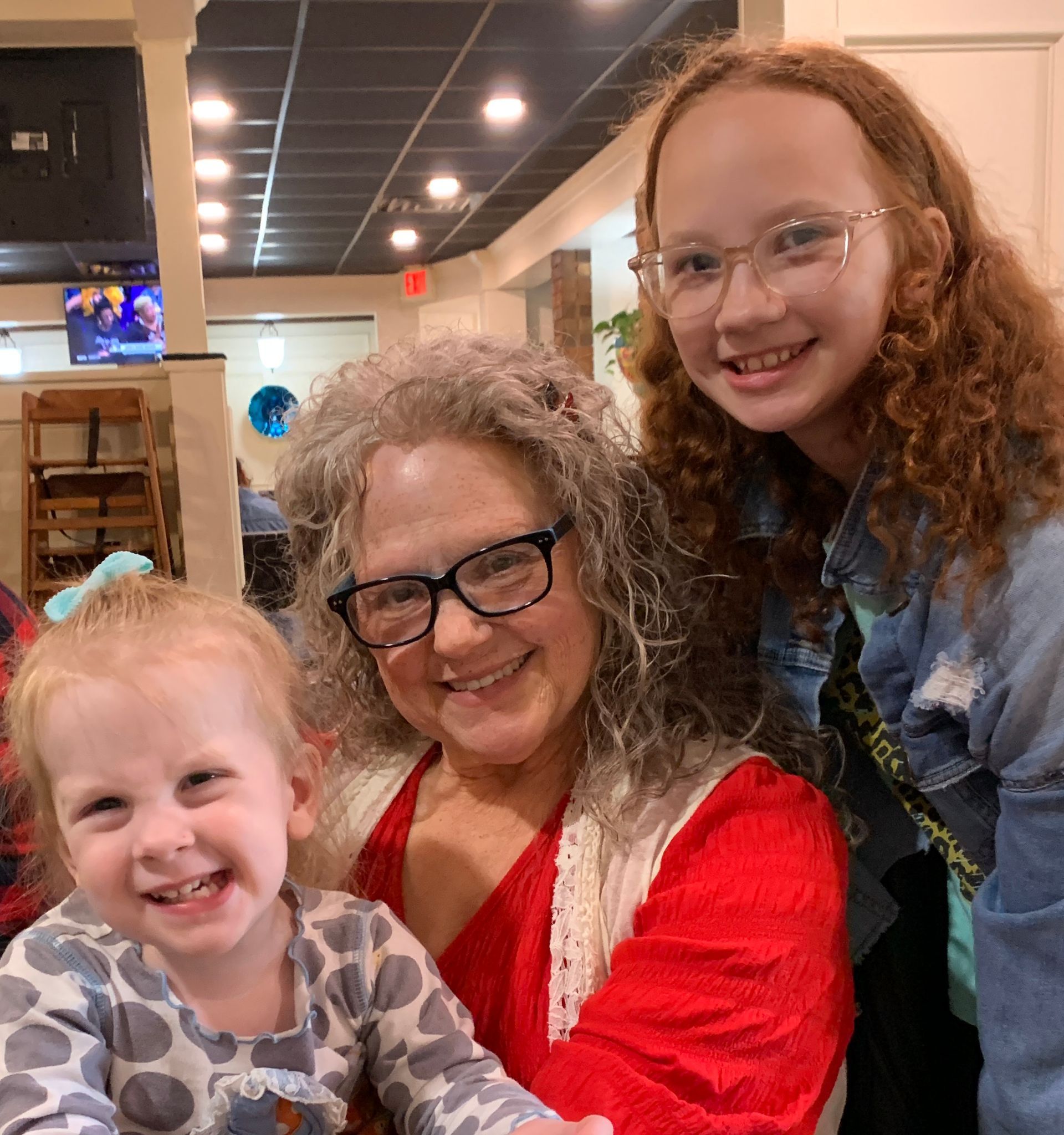 A woman wearing glasses is posing for a picture with two children
