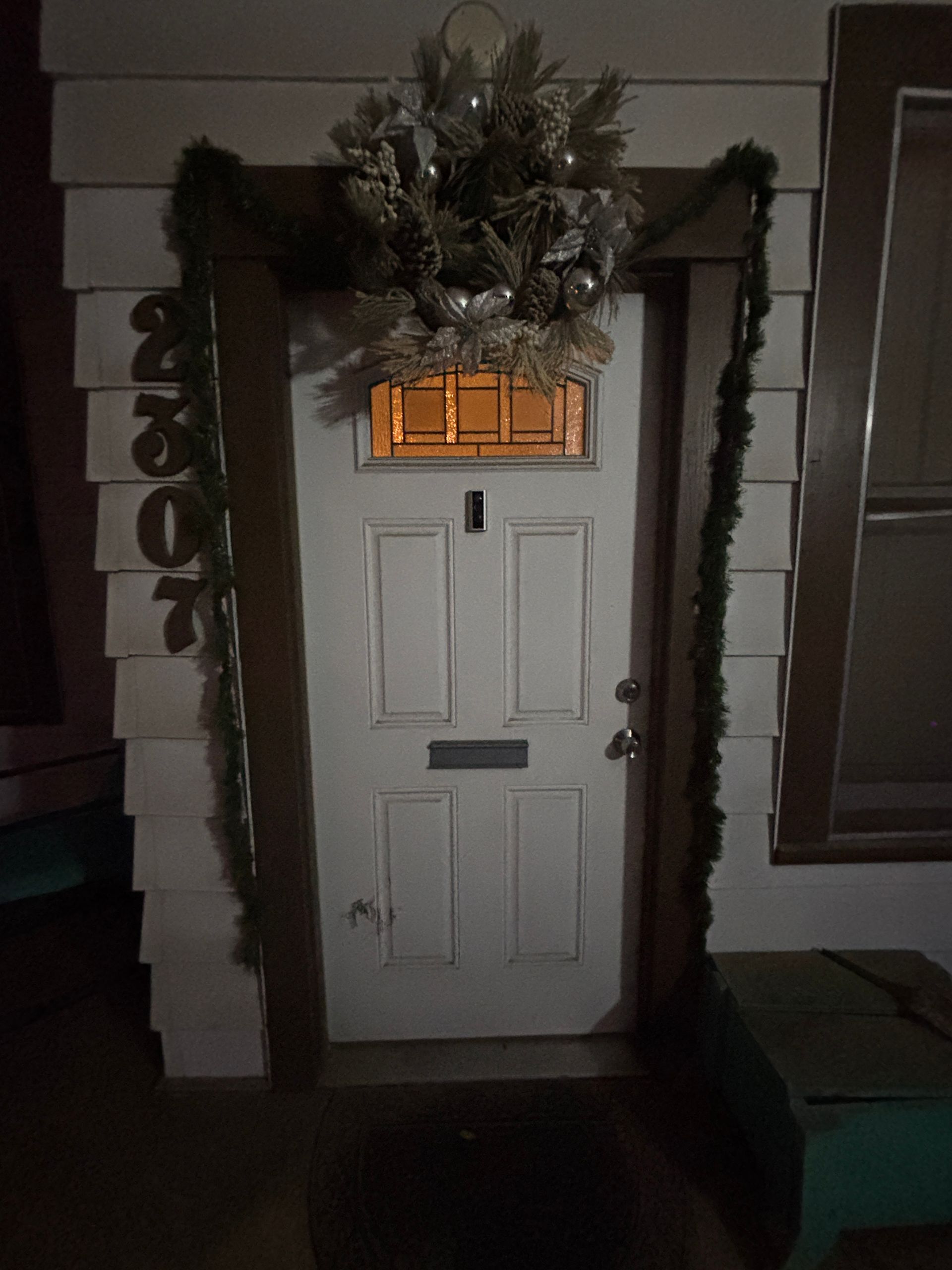 White door with wreath and garland, address numbers on the left.