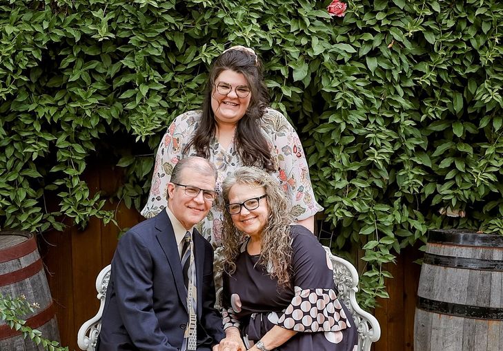 A man and two women are posing for a picture while sitting on a bench.