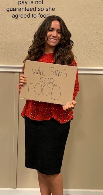 A woman is holding a sign that says pay is not guaranteed so she agreed to food