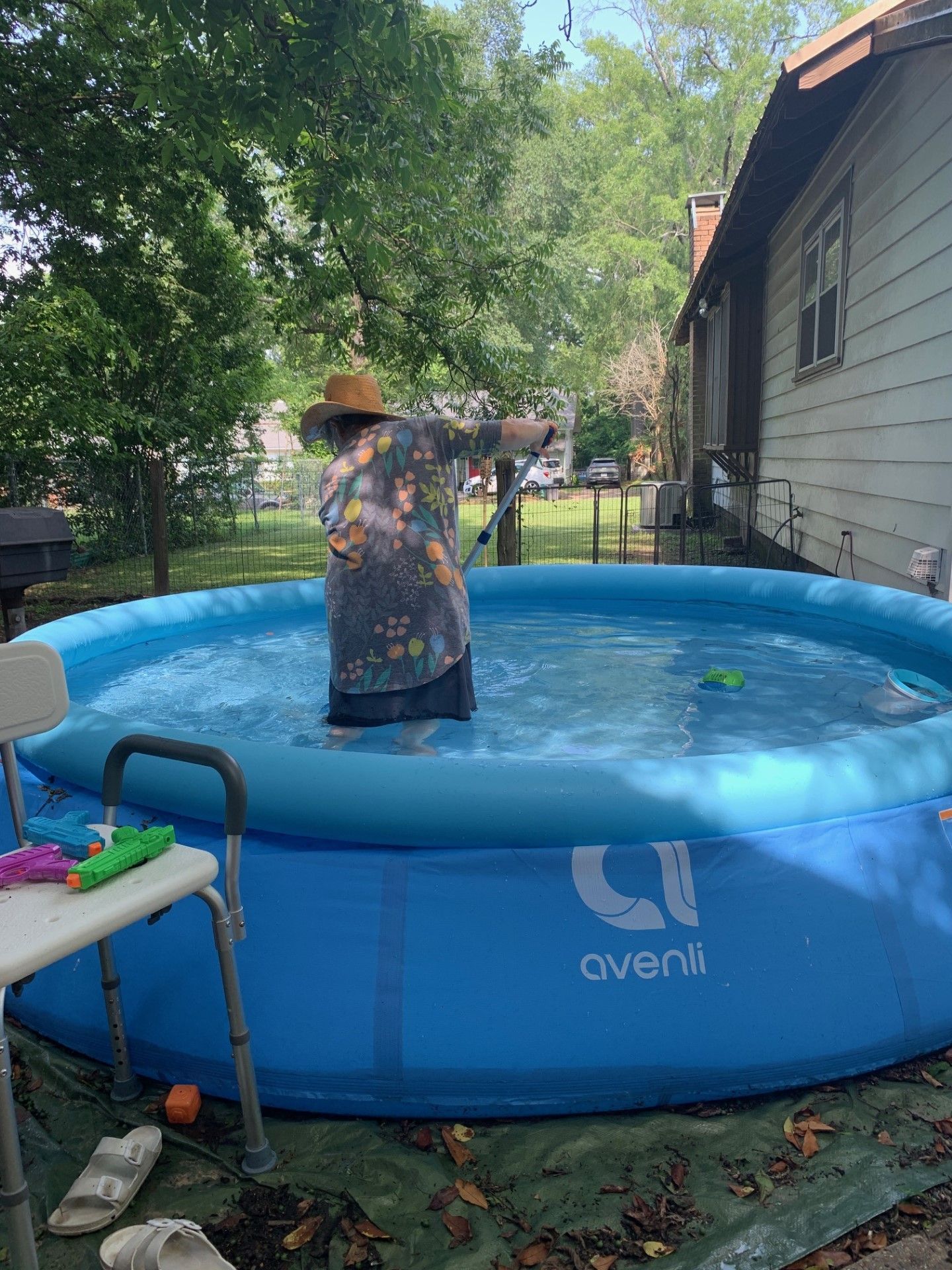 A woman is standing in an inflatable pool in front of a house.
