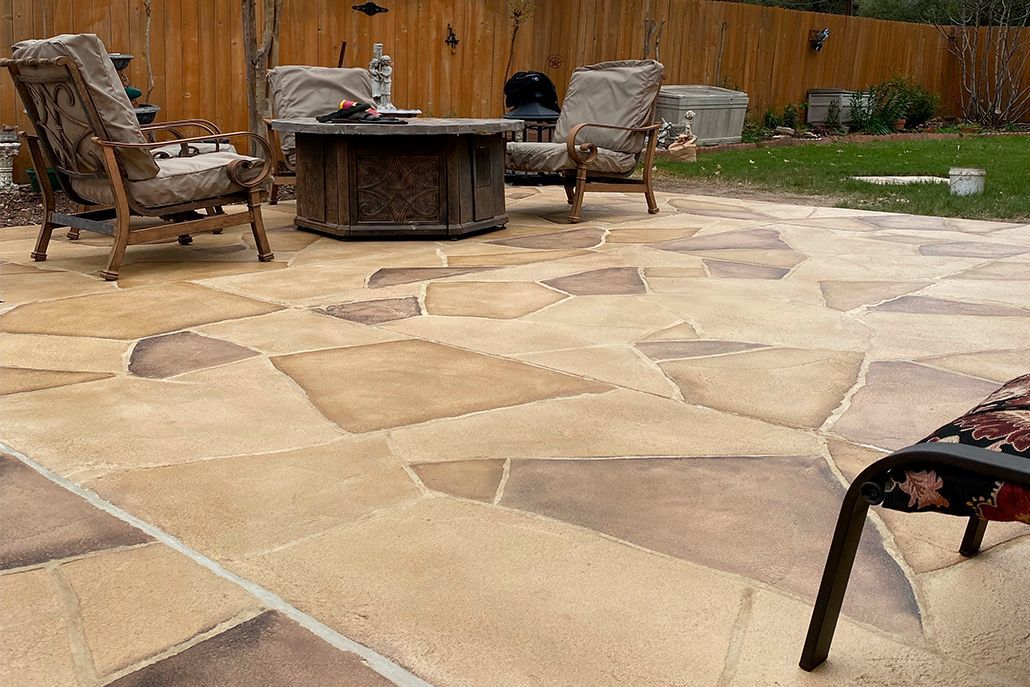 Patio with flagstone tiles, chairs, fire pit, and wooden fence.
