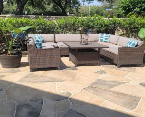 Patio furniture set with a sectional sofa, coffee table, and patterned flagstone flooring outdoors.