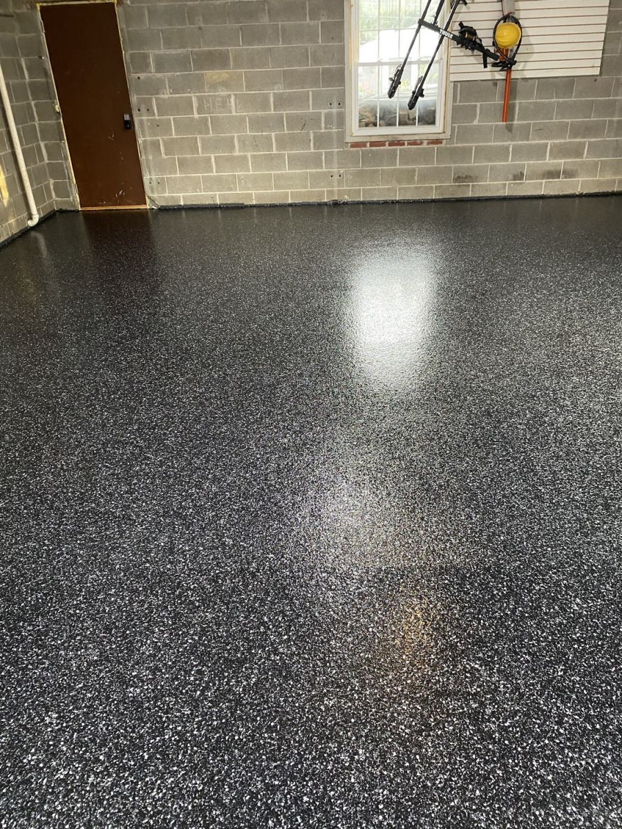 Epoxy garage floor speckled with black, gray, and white chips. Window and door visible.