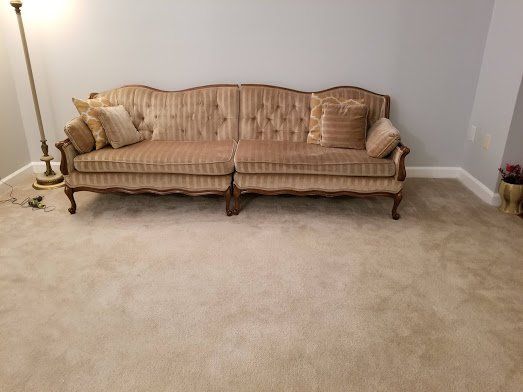 A tufted couch is sitting in a living room next to a lamp.