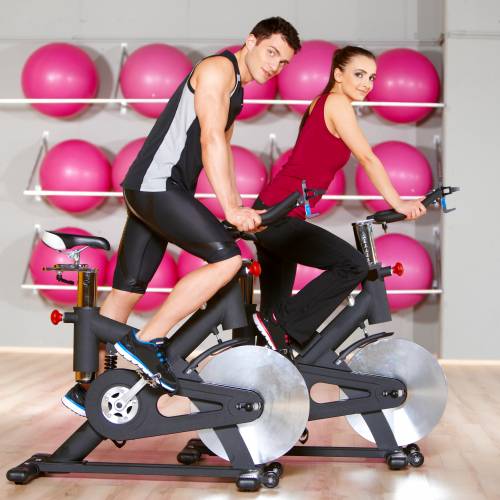 A man and a woman are riding exercise bikes in a gym