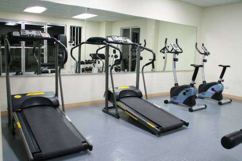 A gym with treadmills and exercise bikes in front of a large mirror.