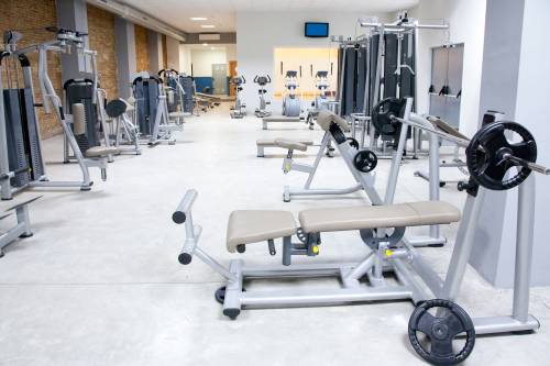 A commercial gym filled with lots of exercise equipment and a bench.