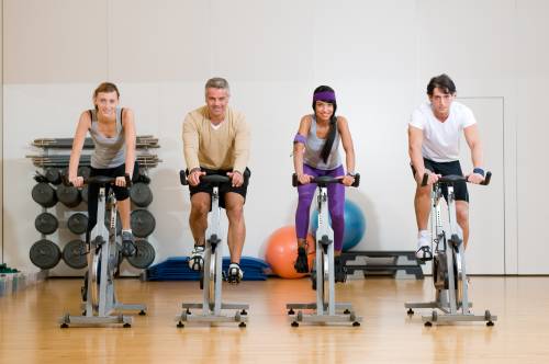 A group of people are riding exercise bikes in a gym.