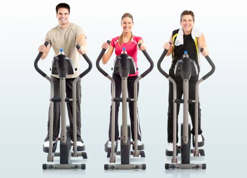 Three people are riding elliptical machines in a gym.