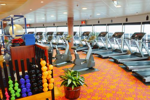 A large gym with a lot of treadmills, bikes  and dumbbells