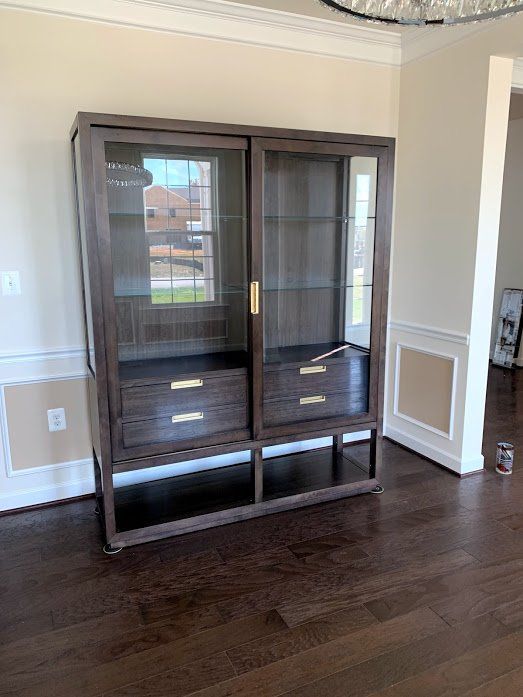 A large wooden cabinet with glass doors and drawers in a living room.