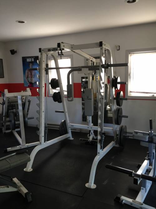 A gym filled with lots of equipment including a smith machine