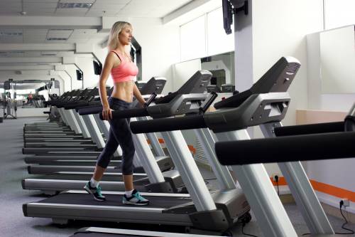 A woman is walking on a treadmill in a gym.