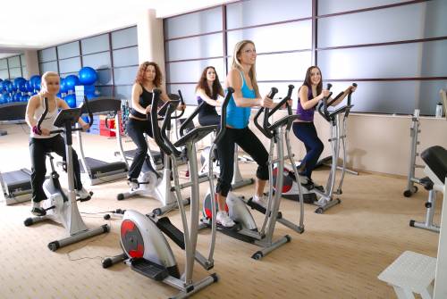 A group of people are riding exercise bikes in a gym.