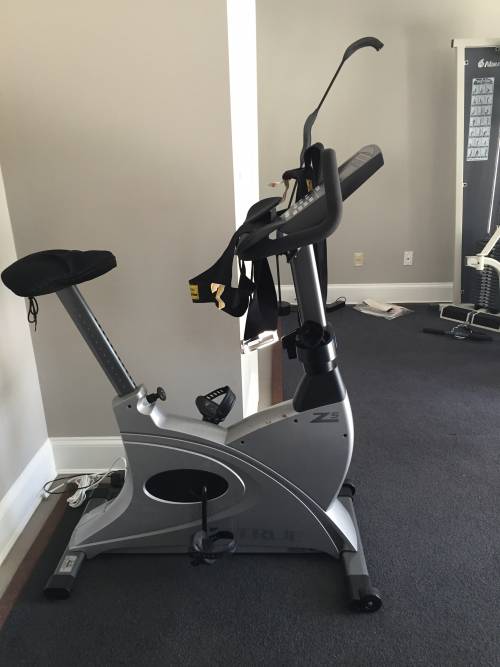 An exercise bike is sitting on a carpeted floor in a room
