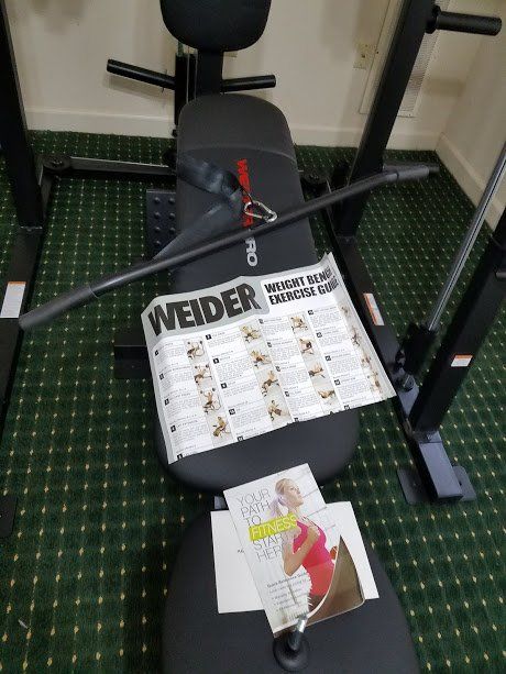 A weider bench is sitting on a green carpet in a gym.