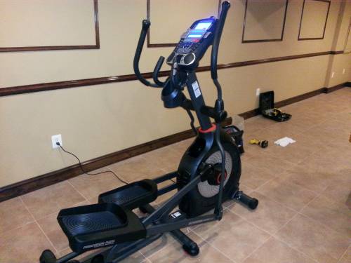 An elliptical machine is sitting on a tiled floor in a room