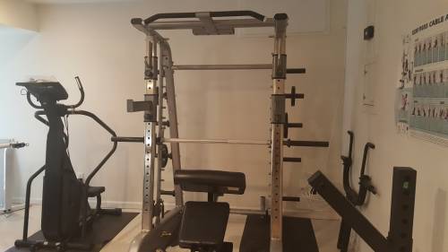 A gym with a barbell rack and a bench