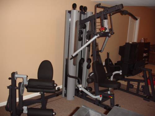 A multi station gym with a lot of equipment including a leg extension machine