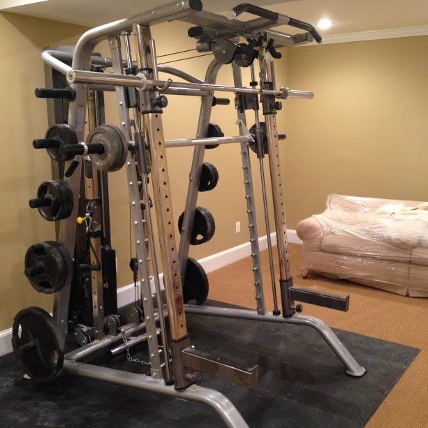 A heavy duty gym with a couch and a bed in the background