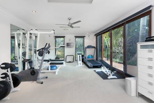 A home gym with a treadmill , dumbbells , and a ceiling fan.