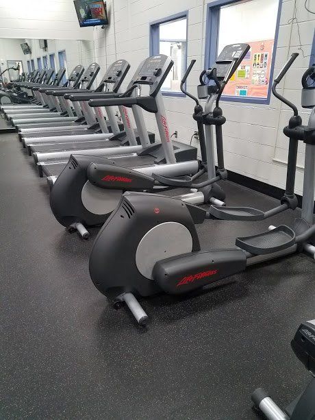 A row of treadmills and ellipticals in a gym.