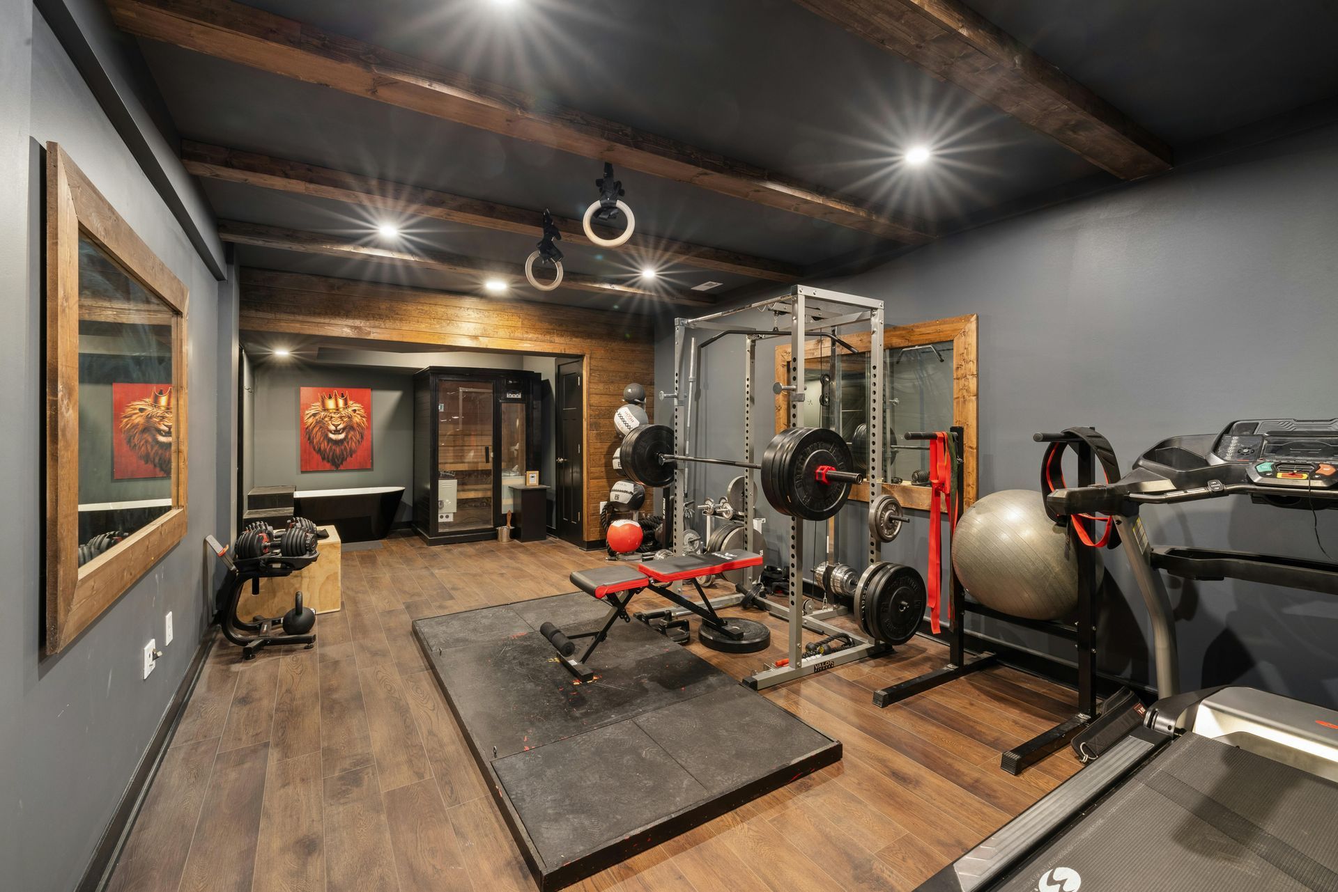 Modern home gym with weight machine, bench, treadmill, and exercise ball on wood floors