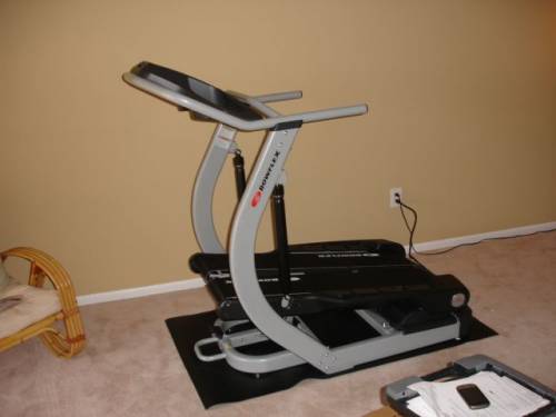 A Bowflex treadmill is sitting on a mat in a room