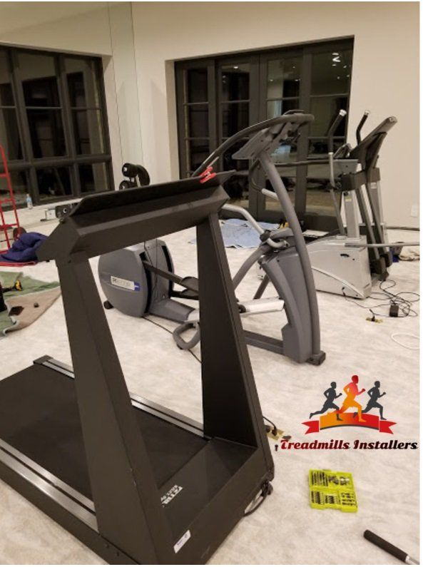 A treadmill is sitting in a room next to an elliptical.
