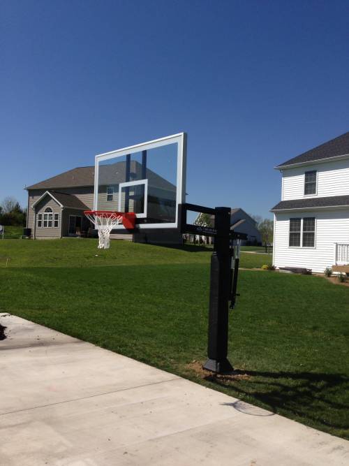 A basketball hoop in a backyard with houses in the background