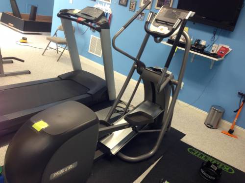 A treadmill and an elliptical are in a gym