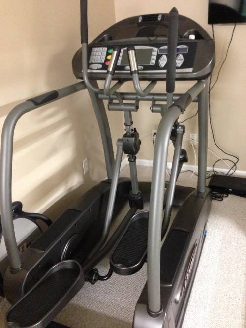 An elliptical machine is sitting on the floor in a room