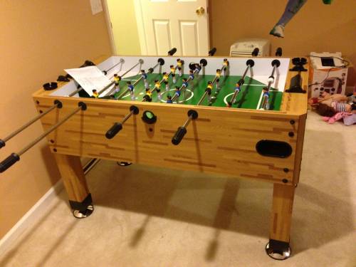 A foosball table is sitting in a room next to a door