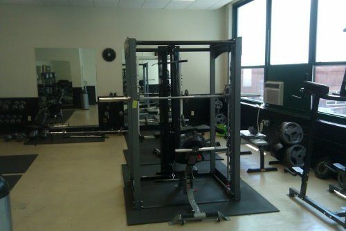 A gym filled with lots of equipment including a squat rack