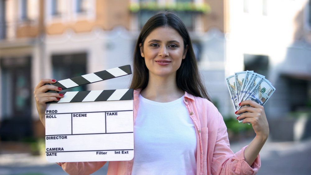 a woman holding a clapperboard and cash for a video production shoot