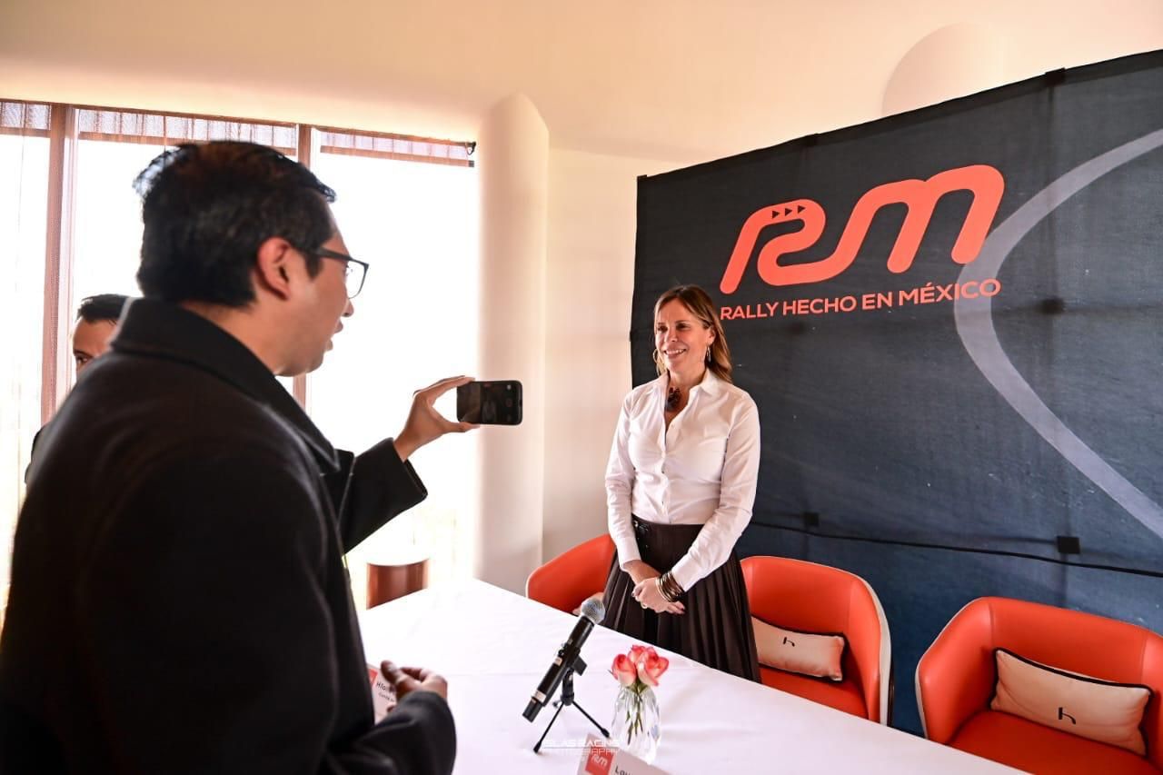 Un hombre está tomando una fotografía de una mujer frente a un cartel que dice RM.