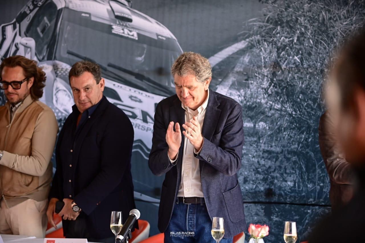 Un grupo de hombres están de pie alrededor de una mesa con copas de vino.