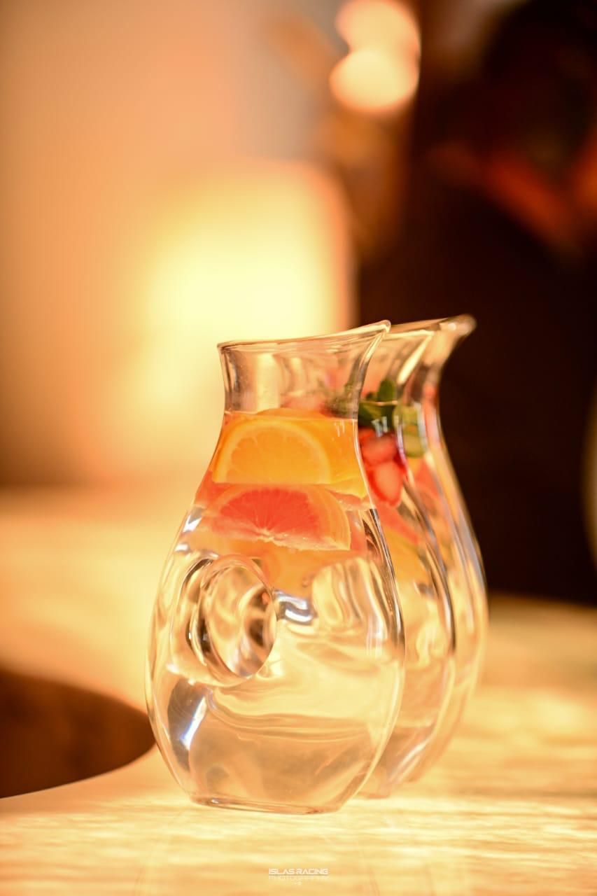 Dos jarras llenas de agua y fruta están sobre una mesa.