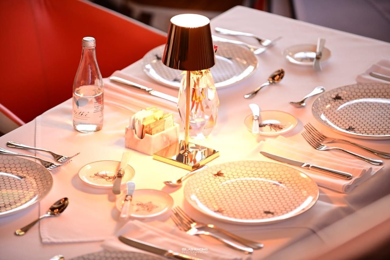 Una mesa con platos, utensilios y una lámpara sobre ella.