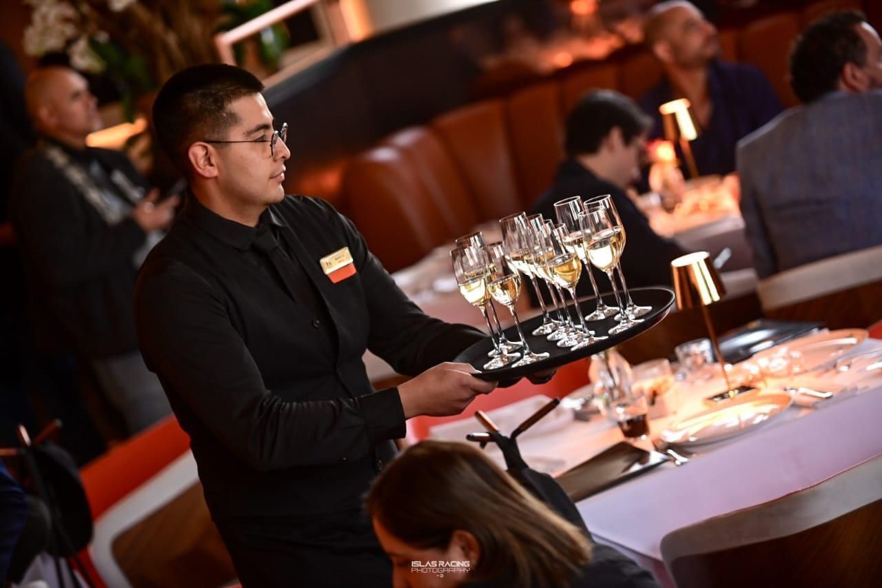Un camarero sostiene una bandeja con copas de vino en un restaurante.
