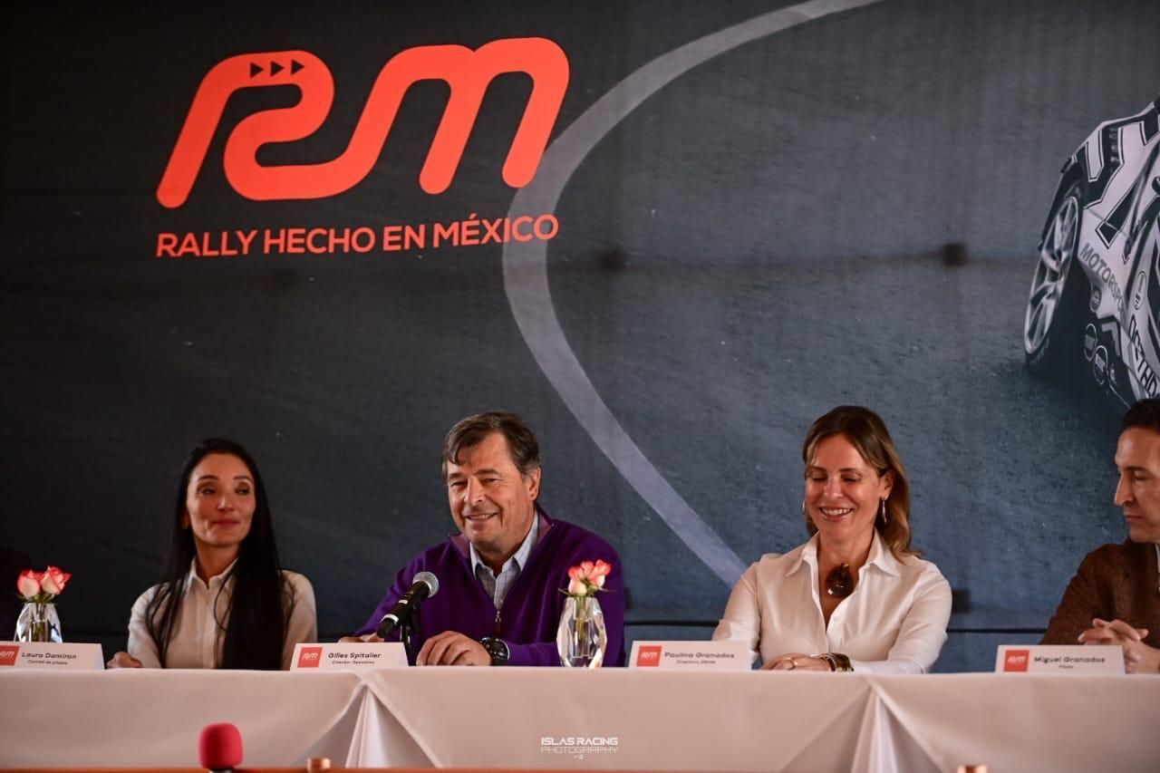 Un grupo de personas sentadas en una mesa frente a un cartel que dice rally hecho en mexico
