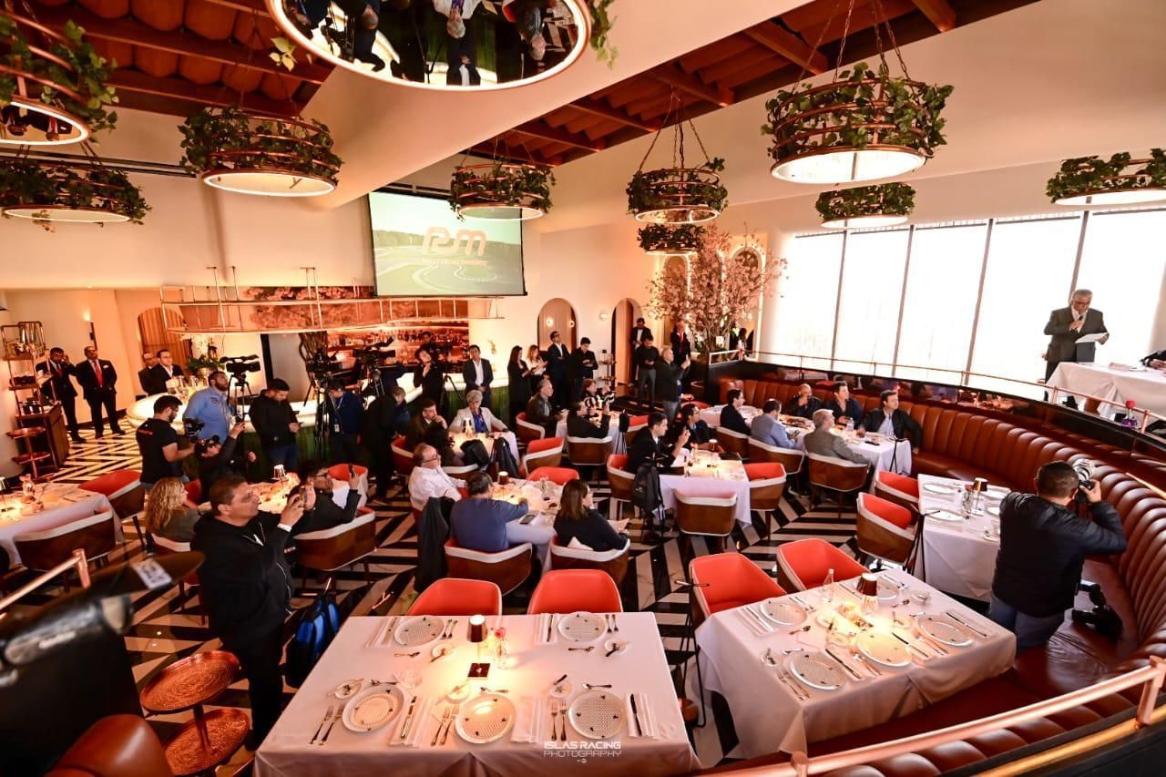 Una gran sala llena de mesas y sillas con gente sentada en ellas.